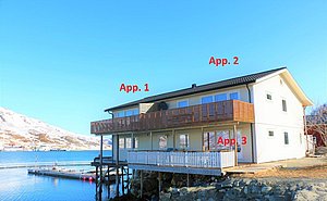 Wohnhaus am Ufer in Nord-Norwegen, aufgeteilt in drei Appartements (App. 1-3). Helle Fassade, Holzdetails, malerische Fjordkulisse. Perfekt für Angelreisen und Naturerlebnisse in malerischer Umgebung. Optimal für Abenteuerlustige und Erholungssuchende.