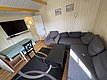 Gemütliches Wohnzimmer in Hitra, Norwegen: moderne graue Couch, eleganter Teppich, Flachbild-TV, Esstisch mit blauer Tischdecke. Idealer Rückzugsort für Entspannung nach einem erfolgreichen Angeltag. Perfekt für Angelurlauber.