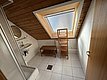 Modernes Badezimmer in einer Angelhütte auf Hitra, Norwegen. Dachfenster fördert Tageslicht, Holzakzente und weiße Fliesen schaffen eine einladende Atmosphäre. Perfekt für entspannende Angelreisen.