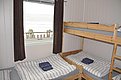 Gemütliches Schlafzimmer in Nord-Norwegen mit Etagenbetten, gestreifter Bettwäsche und Fensterblick auf Fjordlandschaft. Perfekt für Angelurlaube, bietet Komfort und Nähe zur Natur. Optimale Unterkunft für Abenteuerreisende und Angler.