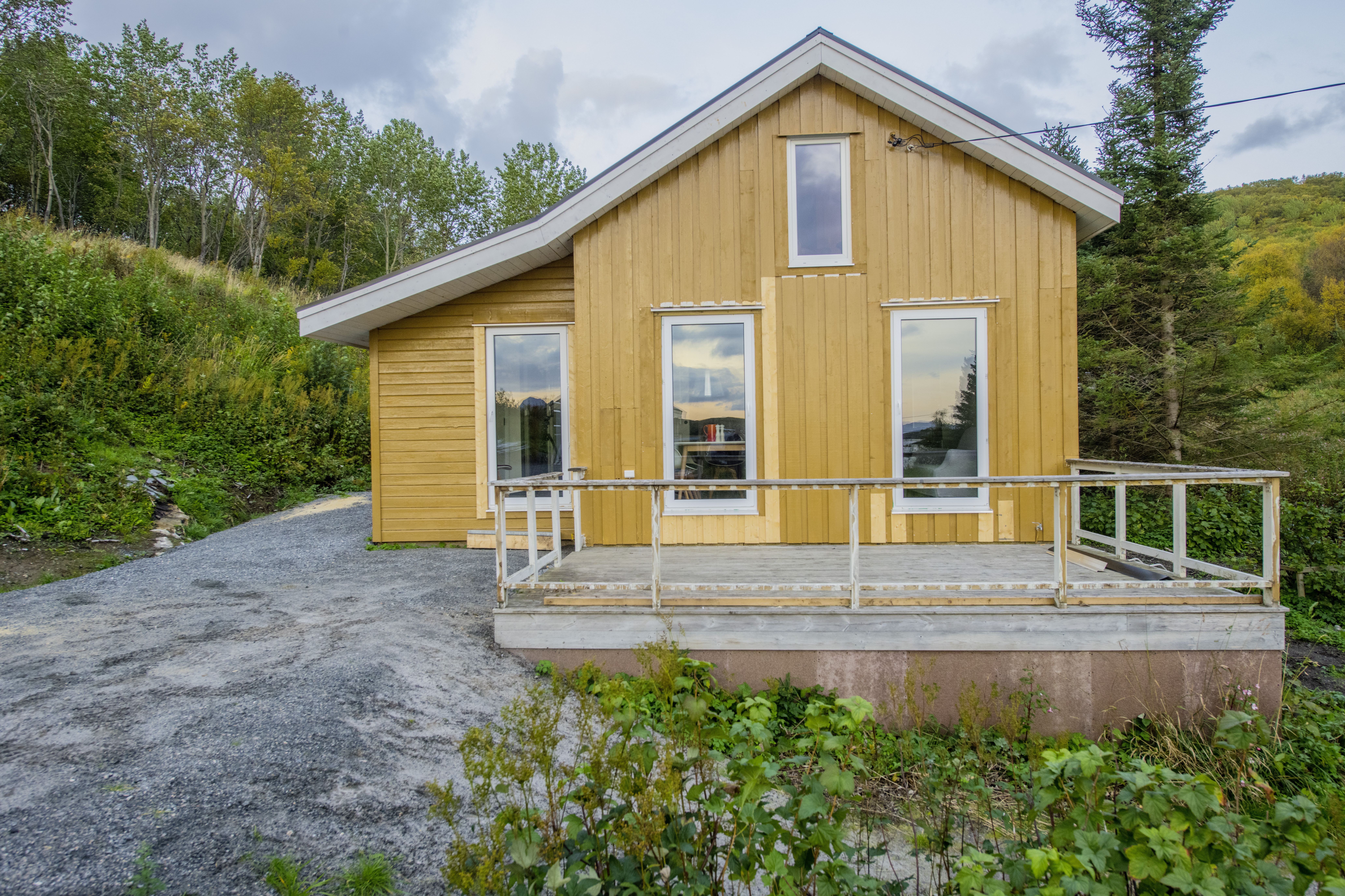 Gelbes Holzhaus in Nordland, Norwegen, umgeben von grüner Landschaft. Perfekt für entspannende Angelurlaube in der Natur, bietet das Haus eine idyllische Kulisse für Outdoor-Abenteuer und entspannte Momente.